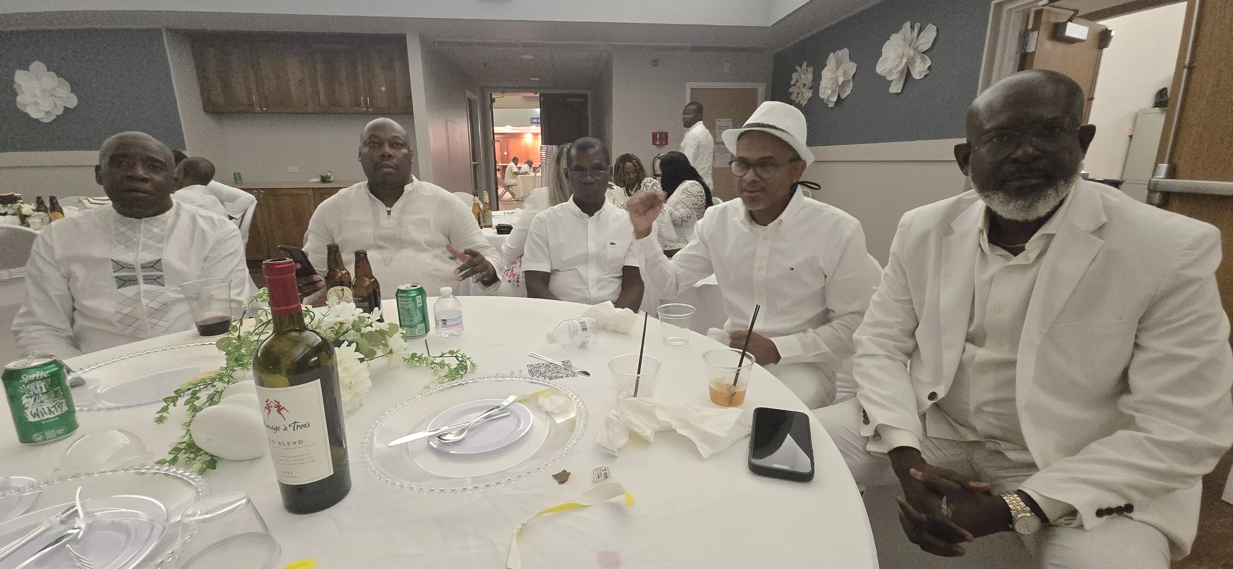 Des membres du Club des Amis autour d'une table à la All White Party